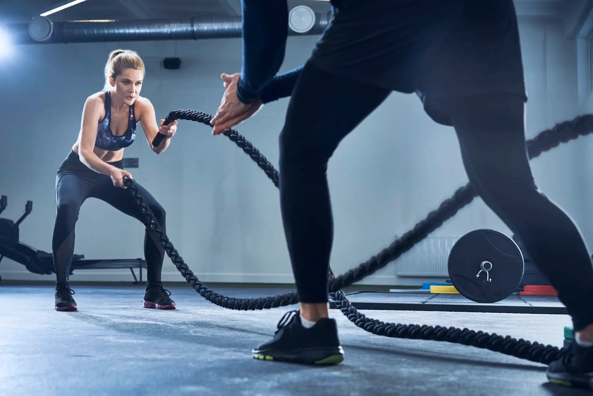 athletic-woman-doing-battlerope-exercise-with-personal-trainer-at-gym-e1677564465697-21