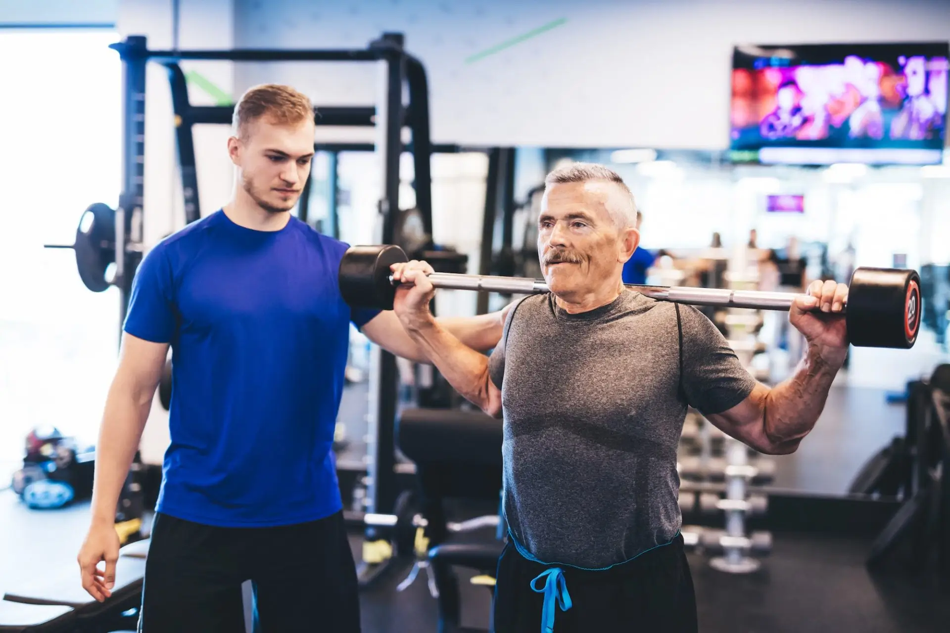 older-man-assisting-senior-man-at-the-gym-e1677564441929-21